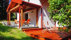 Un'area salotto esterna coperta con sedie in legno e un pavimento in legno.