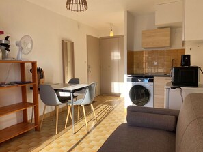Un espace de vie compact comprenant un coin repas, un canapé, un lave-linge et un four à micro-ondes.