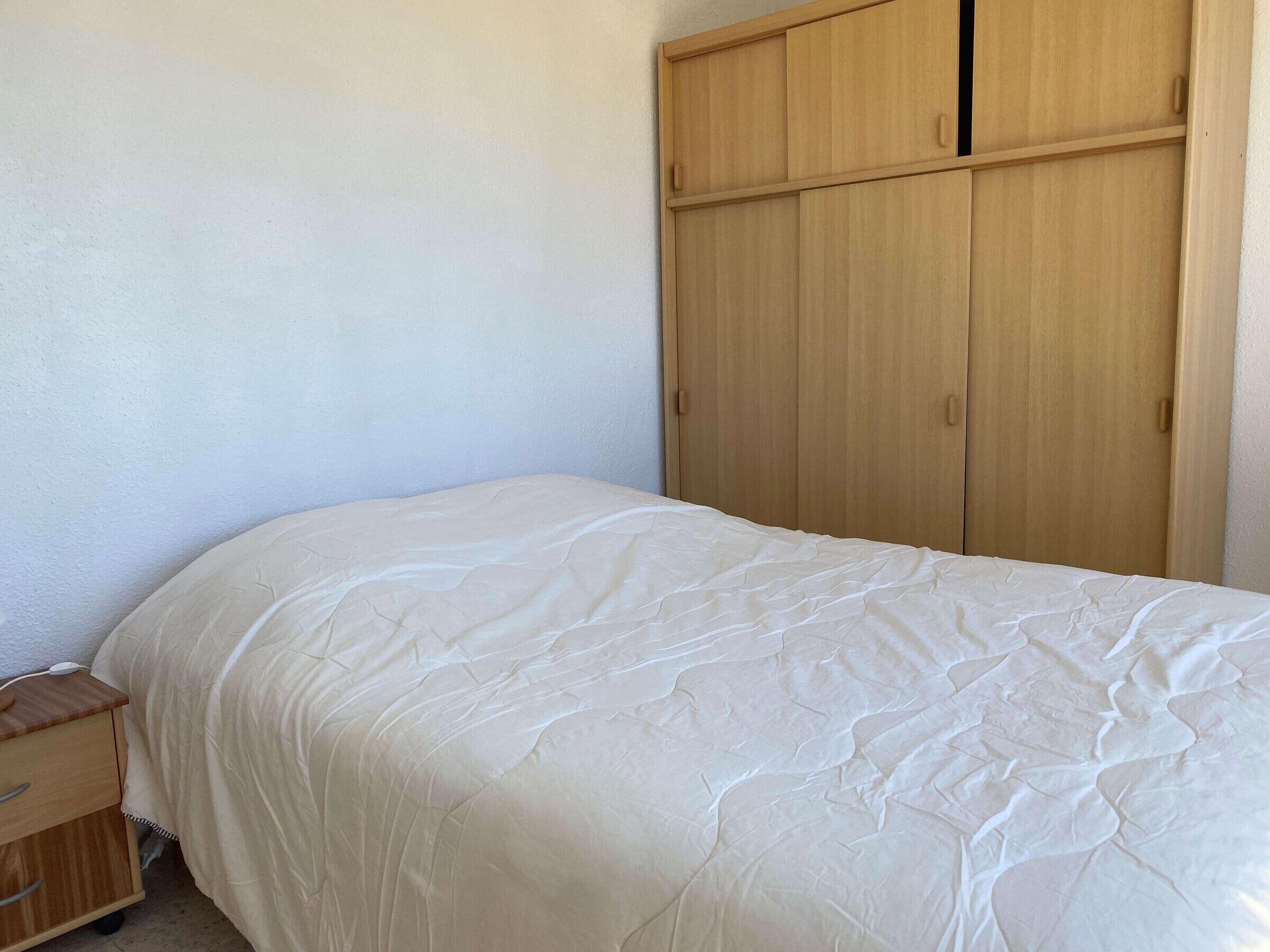 Une chambre à coucher avec un lit, une armoire en bois et une petite table de chevet en bois.