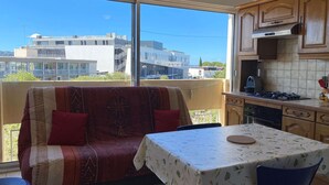 Un balcón con sofá y mesa, una cocina con armarios de madera y vistas a edificios.