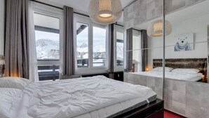 Una camera d'albergo con un letto grande, uno specchio e vista sulle montagne innevate.