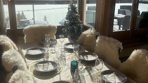 A dining table set for four with a view of a snowy mountain landscape through large windows. - Spacious Apartment 6 People · Balcony · Wifi in Tignes Le Lac (Tignes)