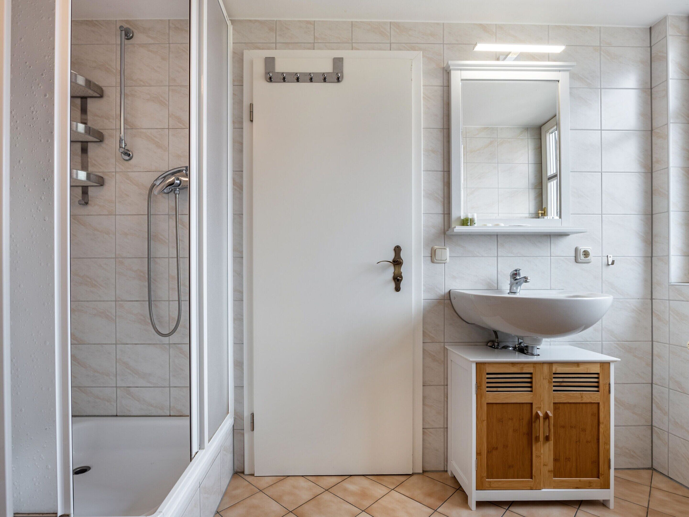 Un bagno con doccia, lavandino e specchio.