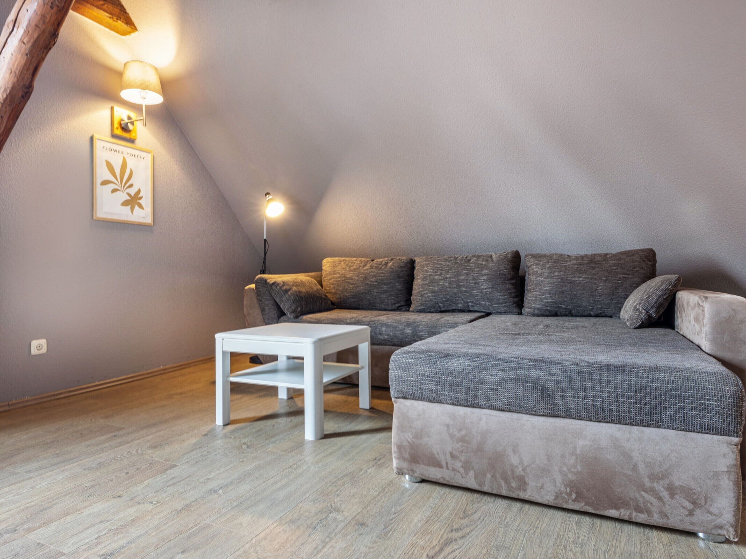A cozy living room with a grey sofa, a white coffee table, and a lamp.