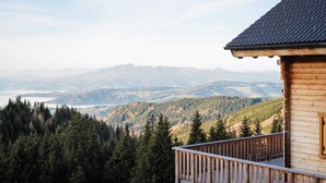 A wooden cabin with a balcony overlooking a forested mountain range. - Holiday Home in Stefan in the Lavanttal With Sauna (Frantschach-Sankt Gertraud)
