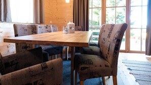 A wooden interior with a large table, benches, and a view through large windows. - Holiday Home in Stefan in the Lavanttal With Sauna (Frantschach-Sankt Gertraud)