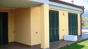 Ein Gebäude mit gelber Fassade, grünen Fensterläden und einer kleinen weißen Bank auf der Veranda.