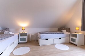 Ein Schlafzimmer mit zwei Betten, Nachttischen und einem kleinen Hocker.
