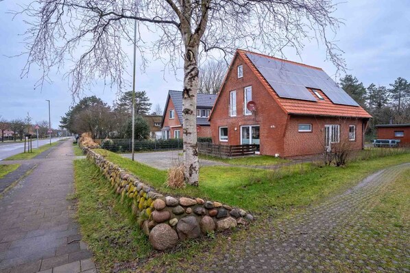 Ein Wohngebiet mit einem Ziegelhaus, das ein Satteldach und Solaranlagen hat.