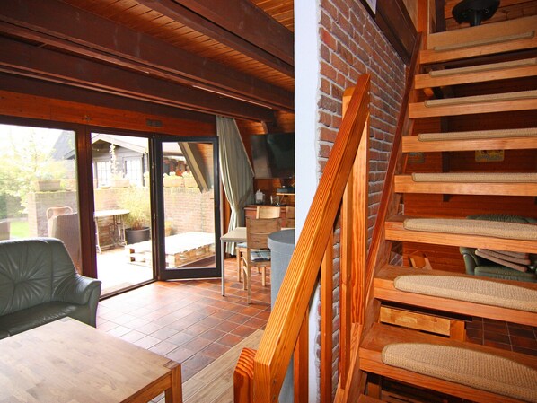 A cozy room with a wooden ceiling, a brick wall, and a sliding glass door leading to an outdoor area. - Ferienparadies in Krusendorf nah am Ostseestrand (Schwedeneck)