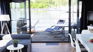 Une chambre moderne avec vue sur un lac, comprenant un canapé, une table à manger et un ordinateur portable posé sur une petite table.