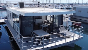 Une structure flottante moderne dotée d’une cuisine, d’un espace salon et offrant une vue sur le port de plaisance.