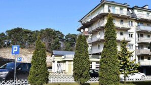 Un immeuble résidentiel à plusieurs étages, doté de balcons, d’un panneau indiquant un espace de stationnement et d’une clôture blanche en bois.