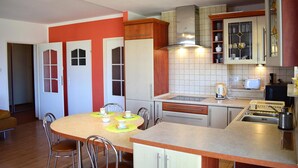 Une cuisine compacte avec un coin repas, comprenant une table ronde, des chaises et les appareils électroménagers de base.