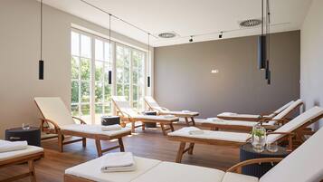 Relax in a serene spa room with lounge chairs and a view of lush greenery.