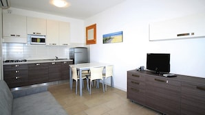 Eine moderne Küche mit Essbereich, einer Couch und einem Fernseher auf einem Schrank.