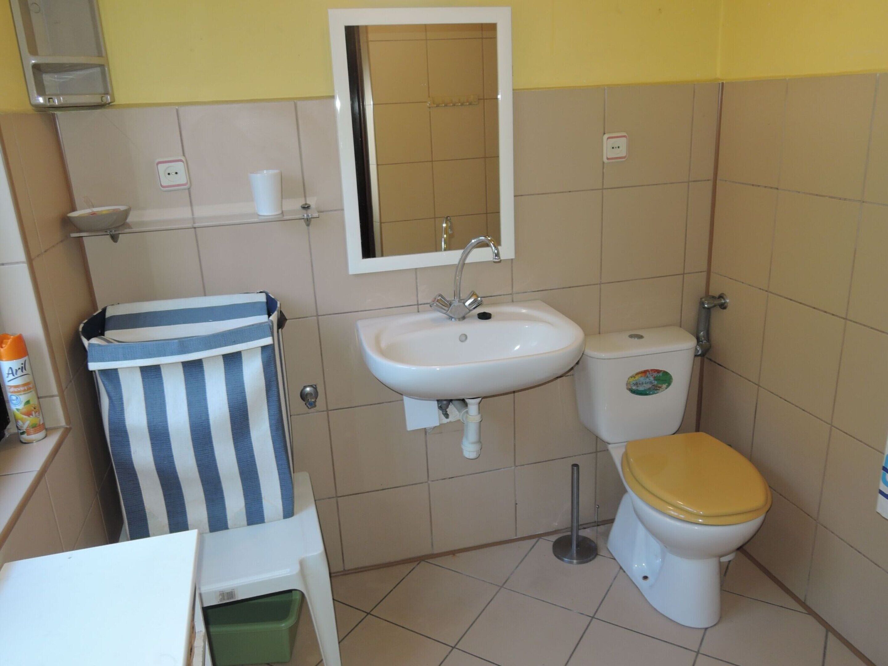 A small bathroom with a sink, mirror, toilet, and a striped towel hanging on the wall.