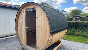 Una sauna in legno con un cartello che riporta la scritta 'HOME DELUXE' e un tetto nero.