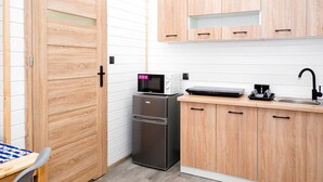 A compact kitchen with wooden cabinets, a microwave, a refrigerator, and a sink. - Comfortable Cottages, Jezierzany (Postomino)
