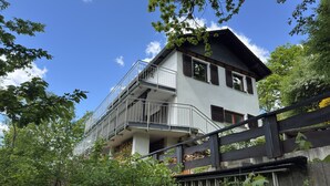 A multi-story building with a balcony, surrounded by lush greenery. - Ferienhaus Sackpfeifenblick, Hatzfeld (Hatzfeld)