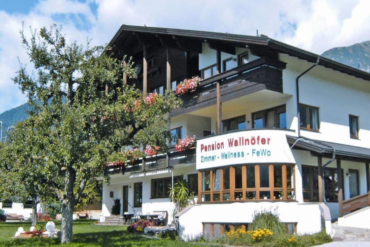 Un edificio con un cartel que dice "Pension Wallöfer Zimmer - Wellness - FeWo".