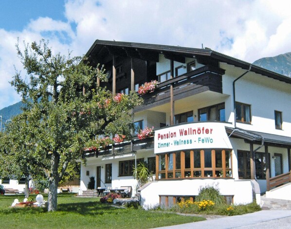 Un edificio con un cartel que dice "Pension Wallöfer Zimmer - Wellness - FeWo".