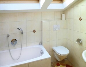 Un baño con bañera, inodoro y tragaluz.