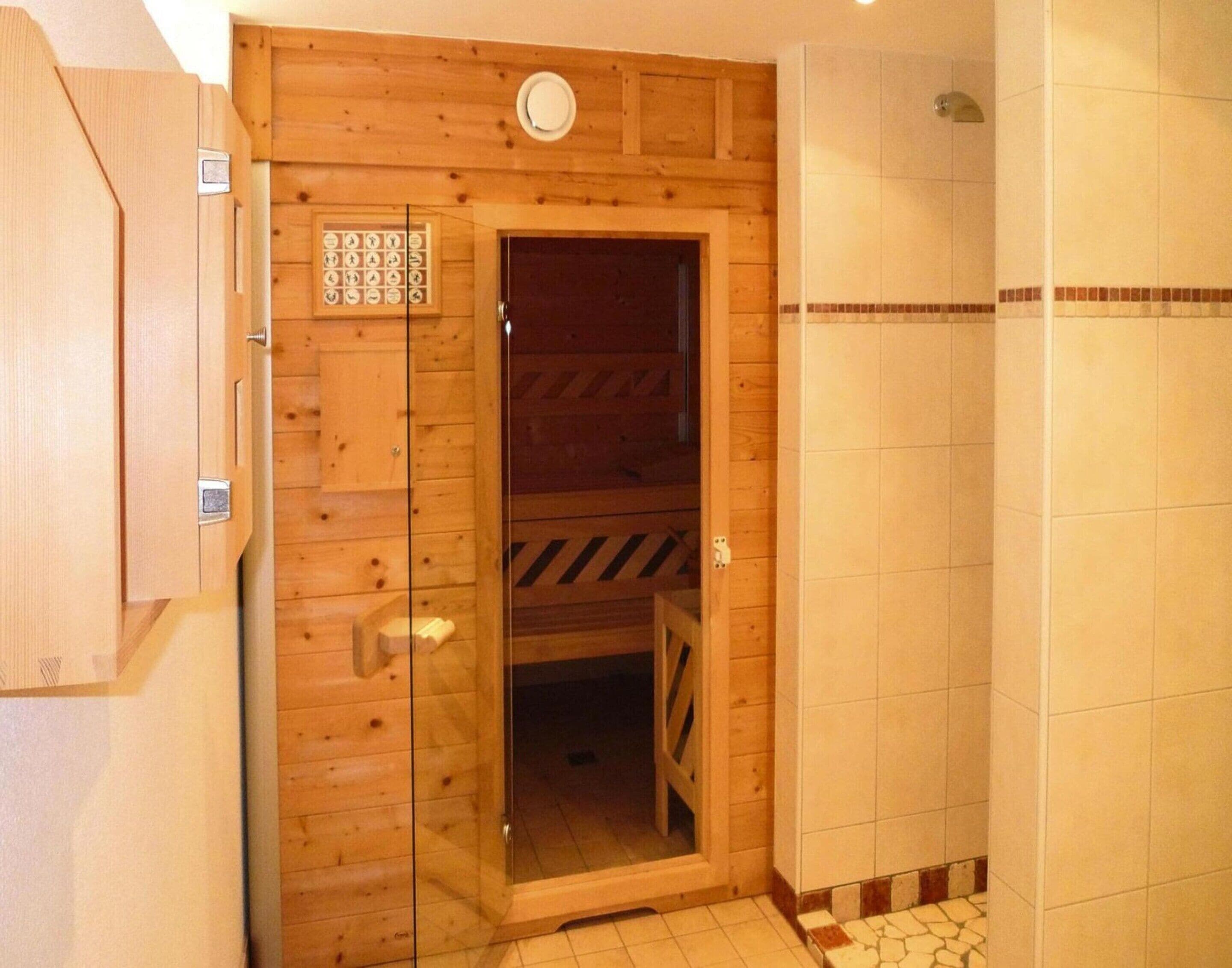 Une porte en bois avec un panneau de verre, un espace de douche carrelé et une petite étagère fixée au mur, sur laquelle sont posés quelques objets.