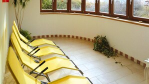 Une salle d’attente avec des chaises jaunes, une grande fenêtre donnant sur un espace verdoyant et une plante posée sur le sol.