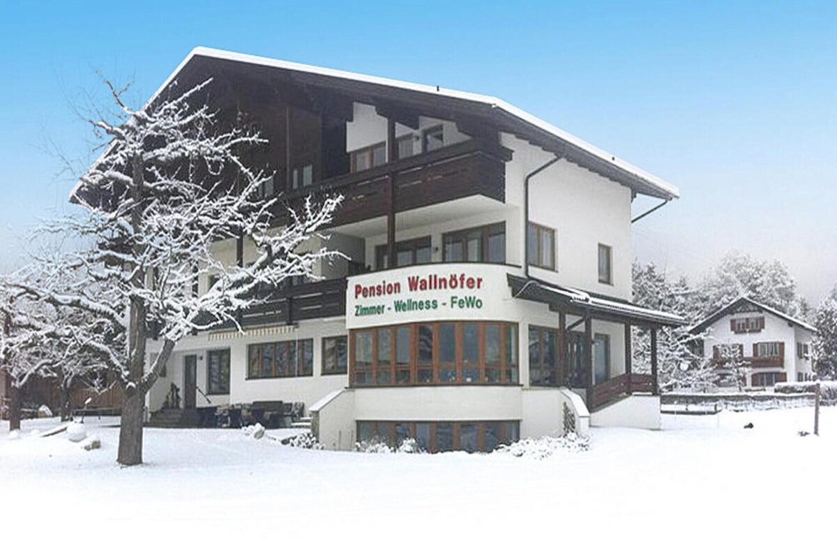 Un edificio de dos pisos con un cartel que dice 'Pension Wallöfer Zimmer - Wellness - FeWo'.