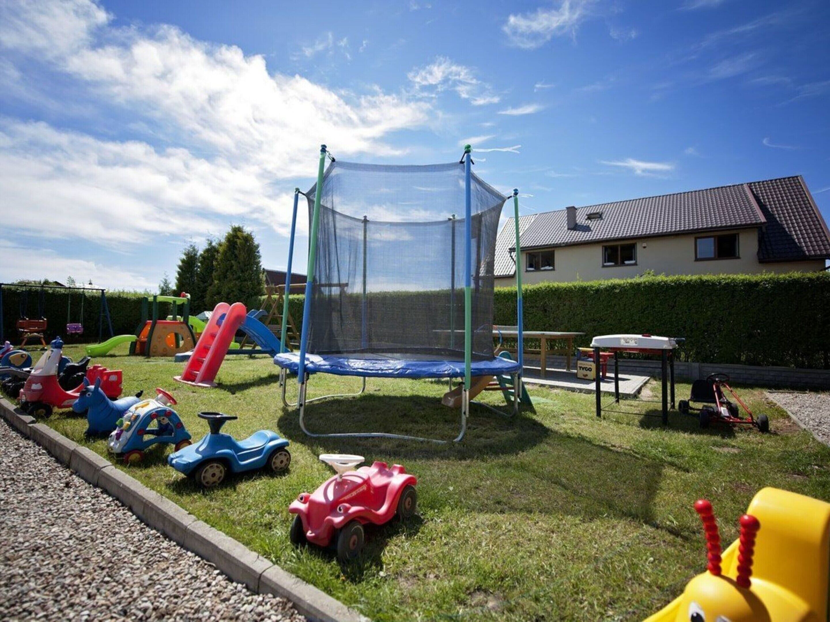 Ein Spielplatz mit Trampolin, Rutschen und Spielzeugautos.