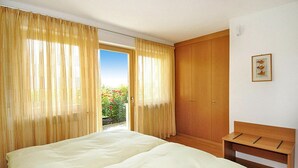 A bedroom with a bed, wooden wardrobe, and a bench. - Apartment in Schlanders With Garden (Silandro)
