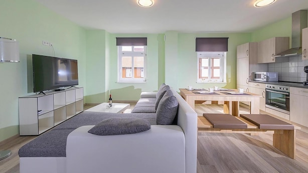 A modern living room with a sofa, TV, and dining area. - Ferienwohnung Remise, Wernigerode (Wernigerode)