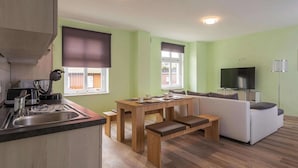 A modern kitchen with a dining area, a sofa, and a TV. - Ferienwohnung Remise, Wernigerode (Wernigerode)