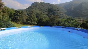 A swimming pool with a blue interior, surrounded by lush greenery and mountains in the background. - Holiday Home in Camaiore With Mountain Views (Camaiore)