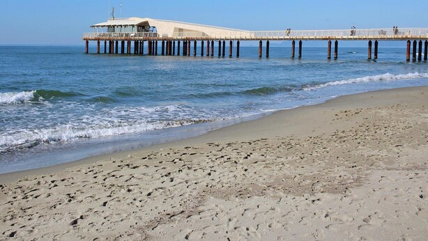 A pier extending into the ocean with a building at the end, a sandy beach, and clear skies. - Holiday Home in Camaiore With Mountain Views (Camaiore)