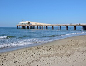 A pier extending into the ocean with a building at the end, a sandy beach, and clear skies. - Holiday Home in Camaiore With Mountain Views (Camaiore)
