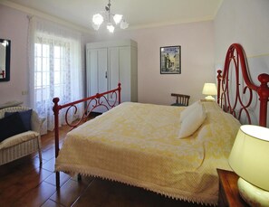 A bedroom with a large bed, a chair, a wardrobe, and a chandelier. - Holiday Home in Camaiore With Mountain Views (Camaiore)