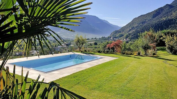 Piscina com vista para montanhas e área gramada.