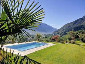 Una piscina con vistas a montañas y un área con césped.