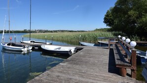 A wooden dock with several boats moored at the end. - Holiday Home With Pool and Sauna (Chmielno)