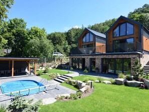 Et moderne hus i to etager med swimmingpool, udendørs siddepladser og en velholdt have.