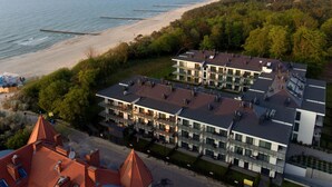 Et moderne hotel med flere etager, store vinduer og udsigt over stranden og havet.