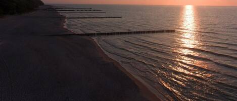 A beach at sunset with a pier extending into the water.