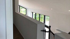 A modern interior with a staircase leading to an upper level, large windows, and a white ceiling.
