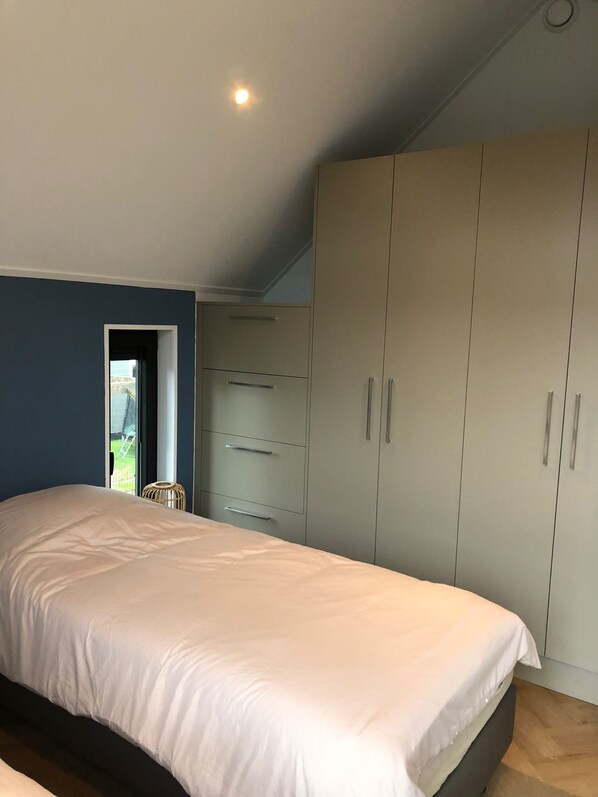 A bedroom with a large bed, a wardrobe, and a window with a view of the outdoors. - Modern Detached Villa (Tzummarum)