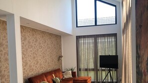 A spacious living room with a large sectional sofa, a coffee table, and a TV on a stand.