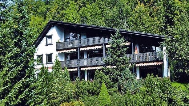 A multi-story building with balconies, surrounded by lush greenery and rocks. - Ferienwohnung im Haus Schiefertal, Wieda (Walkenried)