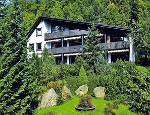 Un edificio a più piani con balconi, immerso nel verde e circondato da rocce.