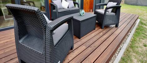 A deck with wicker furniture, including two chairs and a small table.